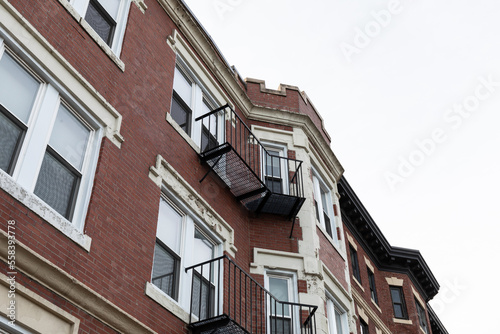Elaborate architectural details on windows, overhangs, and top edge of a classic urban apartment building, metal balconies, horizontal aspect