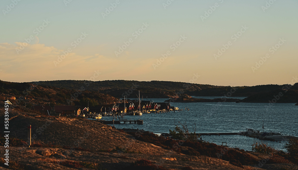 Sunset over a small town in the Tjurpannans nature reserve. Golden sky colors on the idyllic archipelago near Grebbestad. West coast of Sweden. Boats and floating platforms.