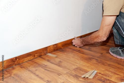 Worker, Carpenter installing laminate flooring. Installing molding trim Vinyl Plank Flooring.
