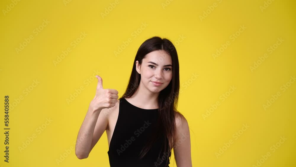 4k slow motion video of one girl showing thumb up on yellow background. 4k slow motion video of one girl showing thumb up on yellow background.