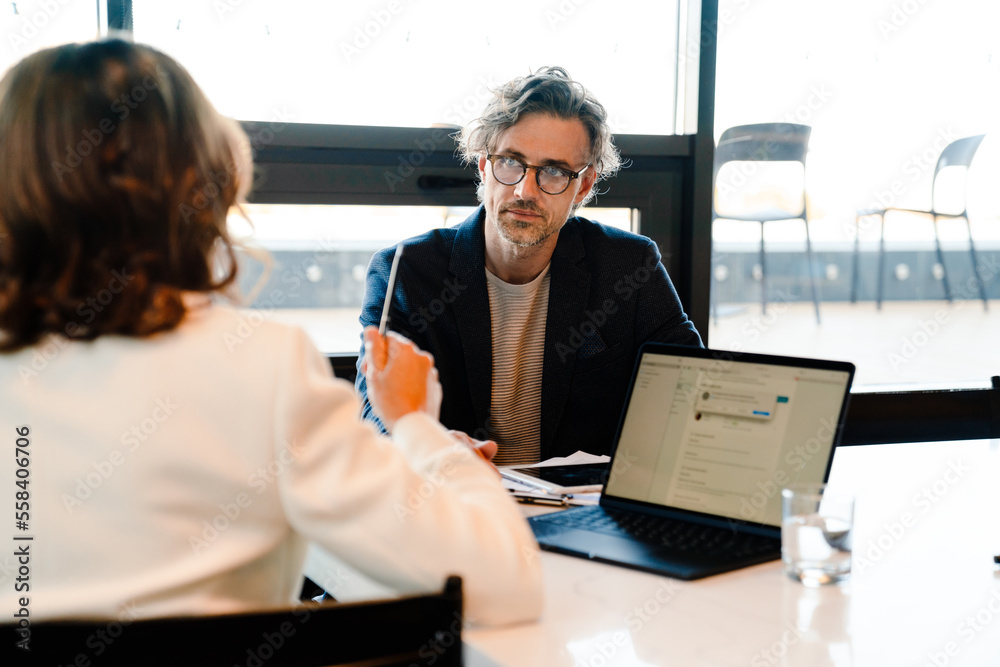 Mature colleagues discussing their project during offline meeting Stock