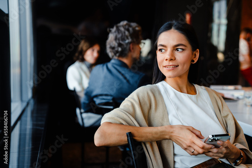 Vászonkép Hispanic young woman smiling and using cellphone during offline meeting