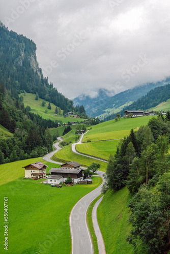 Winding asphalt road through the Grossarl valley, passing alpine farms and green pastures, Grossarl, Austria.