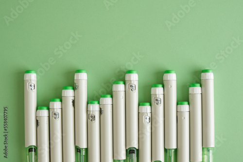 lot of syringe pens with insulin on a green background