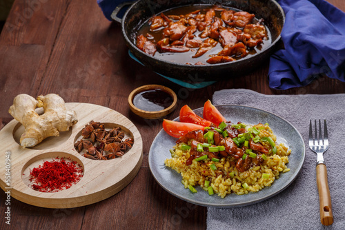 Fried chicken pieces in soy and pad thai sauce in a pan on the table with other food and spices.