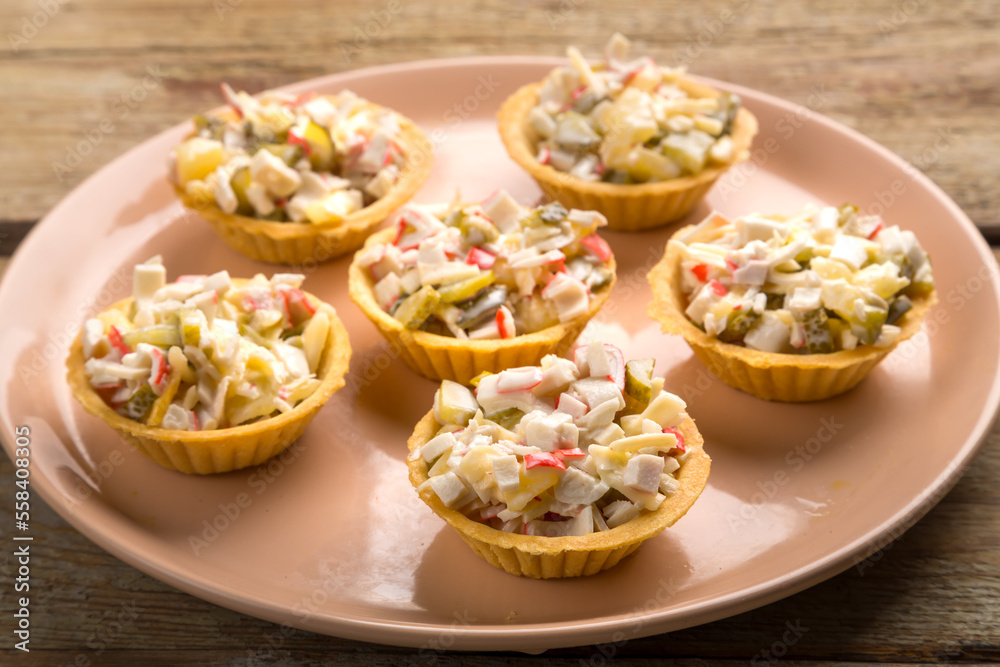 Shrimp salad in tartlets on a plate on a wooden table.