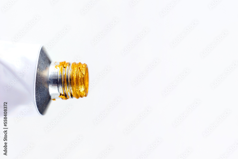 Metal acrylic tube with golden paint for drawing close up on white background with copy space. Metal acrylic tube with golden paint for drawing close up on white background with copy space.