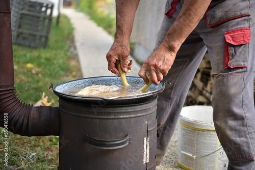 The butcher scalds a domestic hen in hot water in po