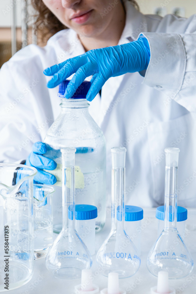 Left handed female scientist opening a sample jar with blue gloves and equipment. Laboratory technician working. Development and chemical, biotechnological, medical and microbiological research. Left handed female scientist opening a sample jar with blue gloves and equipment. Laboratory technician working. Development and chemical, biotechnological, medical and microbiological research.