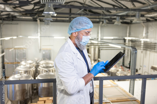 Brewer using a digital device at a beer plant (