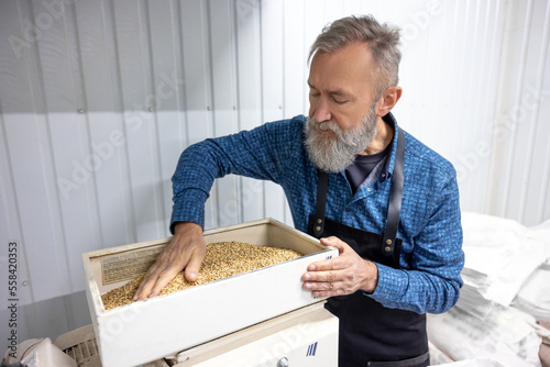 Mature bearded man taking grains from the box photo