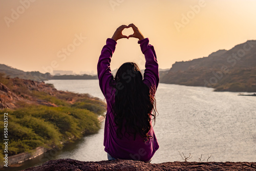 isolated young girl at mountain top with lake view backbit shot from flat angle photo