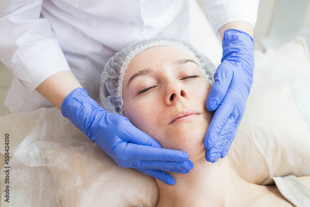 Fototapeta premium The cosmetologist making massage the patient in the spa salon. Facial care.