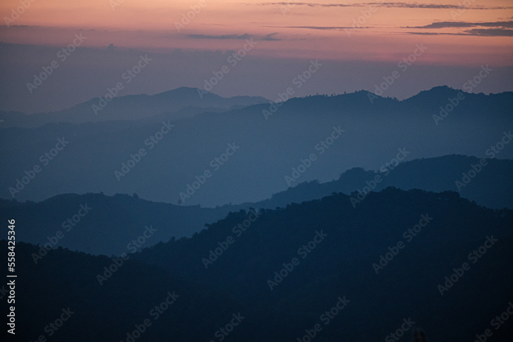 morning sunrise revealed misty layer landscape with trees and meadow as foreground Doi Kad Phi forest park Chiang Rai Thailand December 2022
