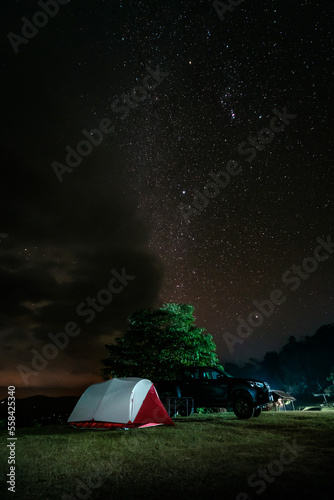 campers setting their tent and truck under starry night sky on Doi Kad Phi forest park campground Chiang Rai Thailand December 2022