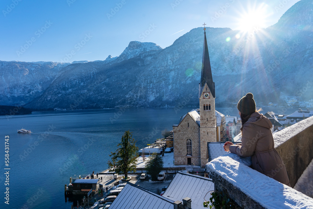 beautiful cityscape of the special city Hallstatt in Austria Salzkammergut snowy winter mountains and lake with tourist woman