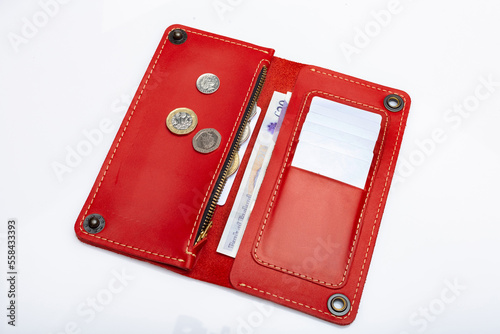 Big red leather wallet on a button on a white background. Coins and money