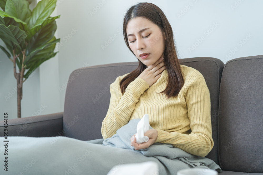 Sick, hurt or pain asian young woman, girl with sore throat, headache have a fever, flu and use tissues paper sneezing nose, runny sitting on sofa bed at home. Health care person on virus seasonal. Sick, hurt or pain asian young woman, girl with sore throat, headache have a fever, flu and use tissues paper sneezing nose, runny sitting on sofa bed at home. Health care person on virus seasonal.