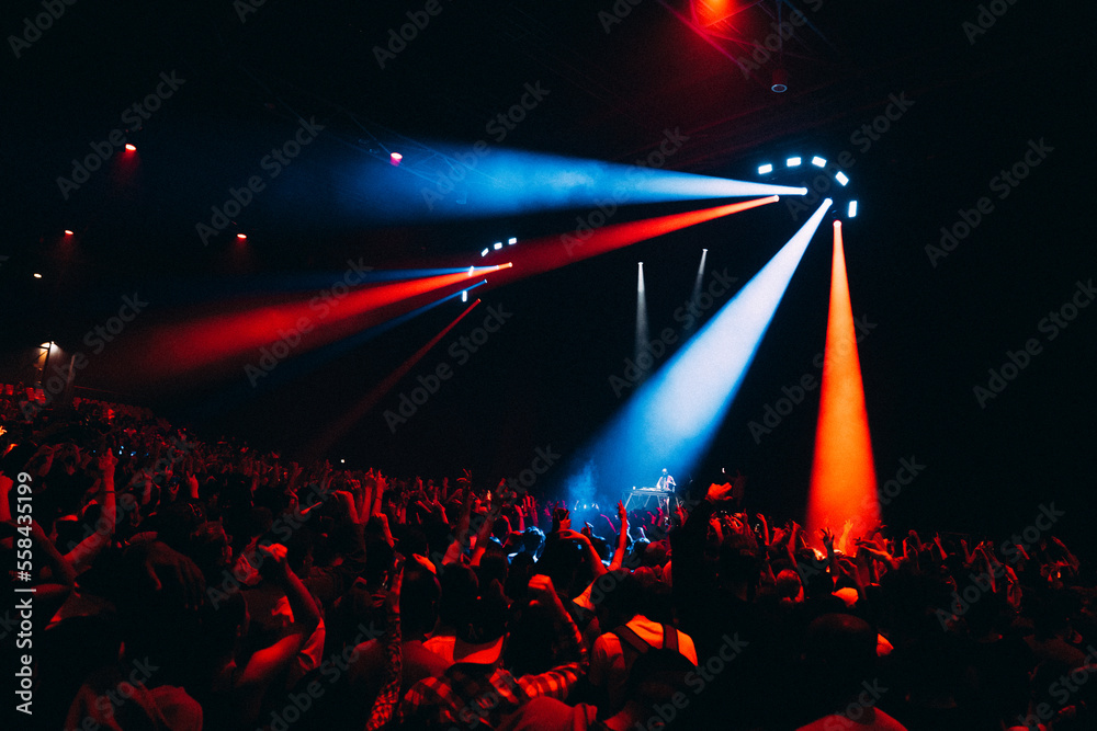 Foule en délire lors d'une fête concert de musique avec jeux de lumières comme boîte de nuit, bleu et rouge