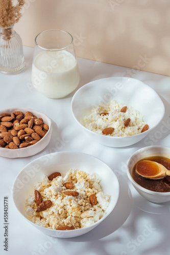 cottage cheese in a white bowl with nuts and honey on a light ba