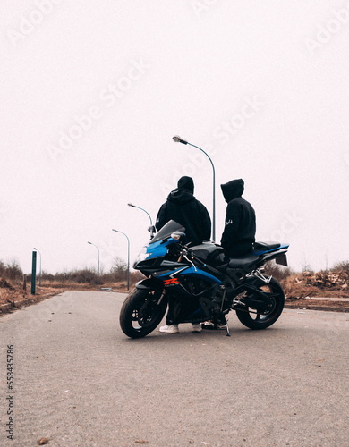 Deux hommes biker motard devant une route avec des lampadaires et une moto 