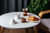 coffee and croissant on a plate on a white table in the living r
