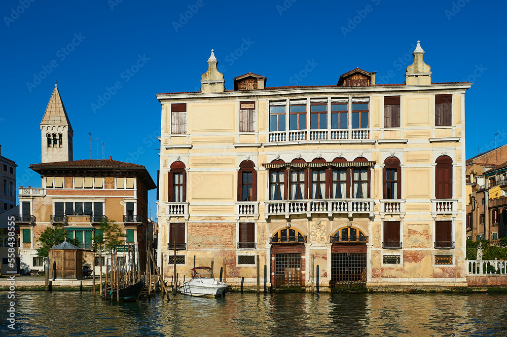 View of a typical Venetian facade with its façade damaged by the effect of water and a wooden pier for small boats