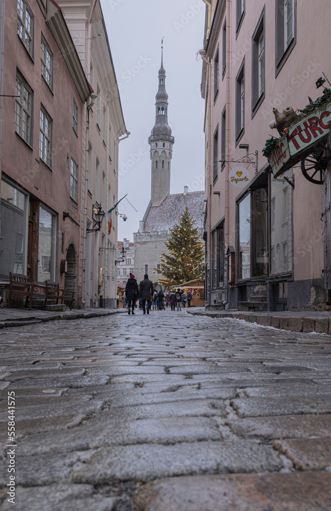 Christmas tree and market down a cobblestone street in Estonia tower in the background