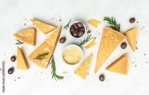 Pieces of parmigiano reggiano or parmesan cheese. Sliced and grated parmesan cheese with rosemary on a light table, Long banner format. top view