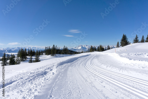 Winter mountain landscape, sunny day in Salzburg Alps. Winter road with groomed ski trails.