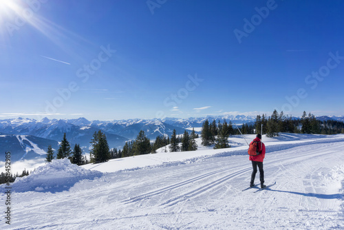 Winter mountain landscape, sunny day in Salzburg Alps. Single cross-country skier on groomed ski trails on top of the Rossbrand Mountain.