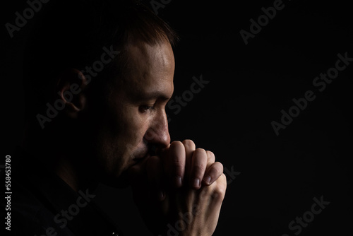 Fototapet Close up of faithful mature man praying, hands folded in worship to god with head down and eyes closed in religious fervor
