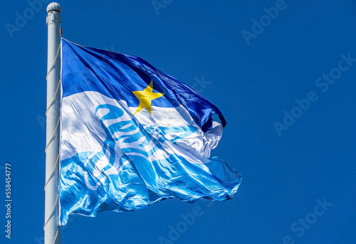 The flag of the Zenit football team on a flagpole, fluttering in the wind, against the sky.