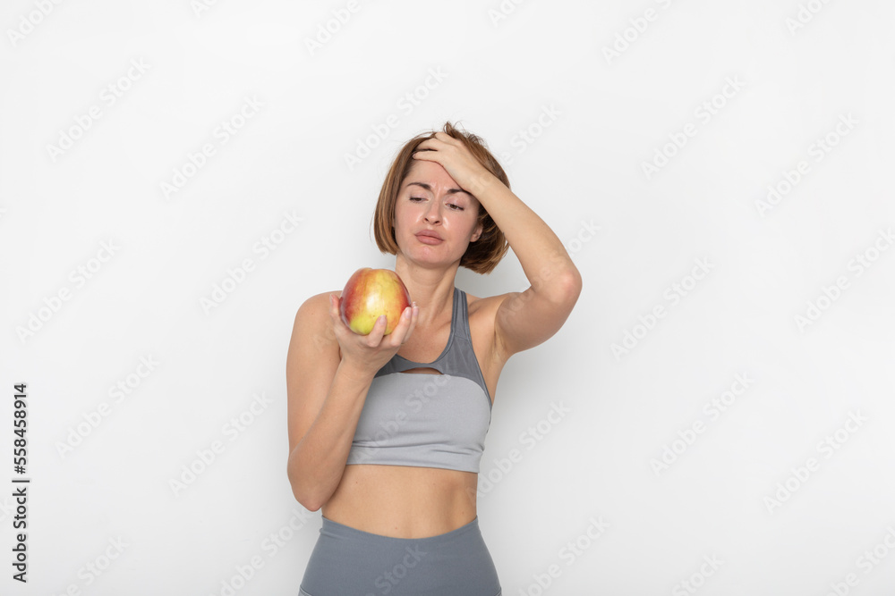 Close up portrait of pretty woman in sportswear holding apple isolated on white background. Healthy lifestyle concept Close up portrait of pretty woman in sportswear holding apple isolated on white background. Healthy lifestyle concept