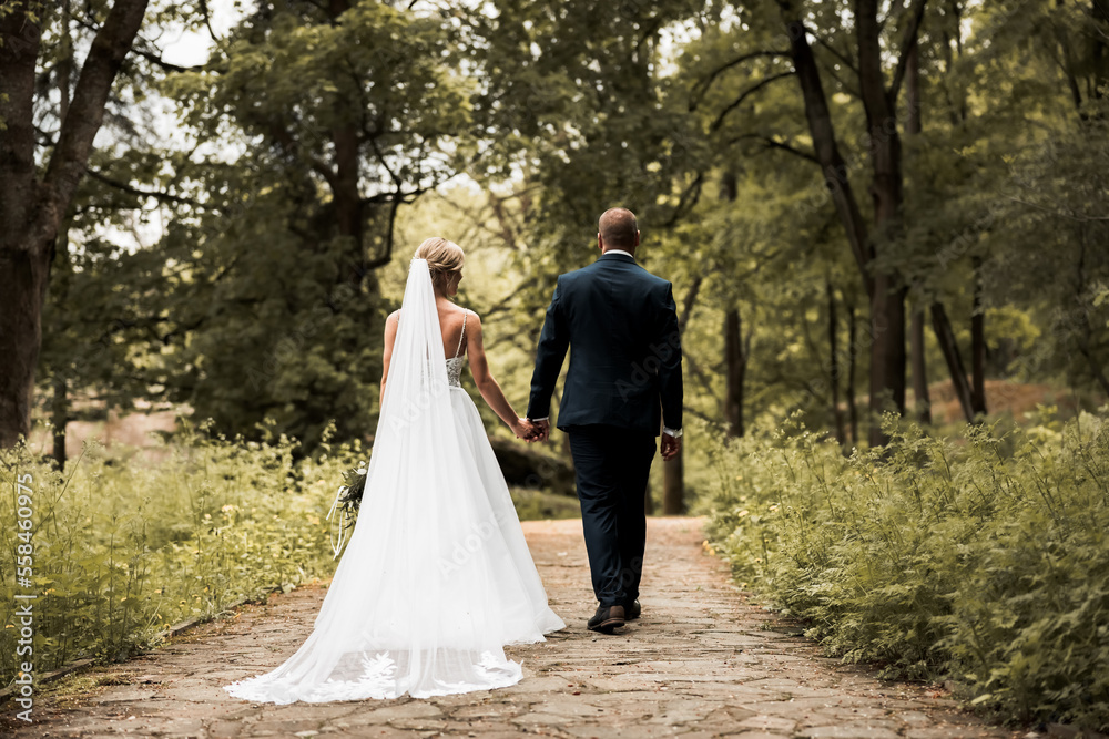 The bride and groom hold hands and look to the future in the middle of nature, the newlyweds walk together,wedding photography,until death do us part The bride and groom hold hands and look to the future in the middle of nature, the newlyweds walk together,wedding photography,until death do us part