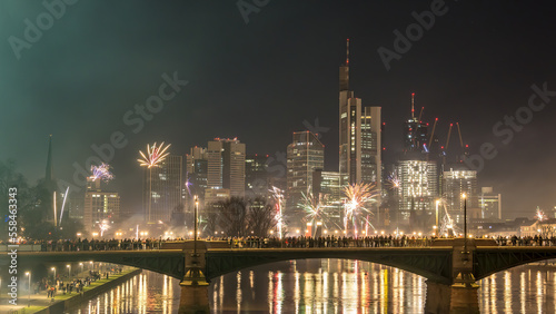 New years eve with fireworks above the skyline of Frankfurt - Main at night at a cold day in winter with colorful reflections in the water.