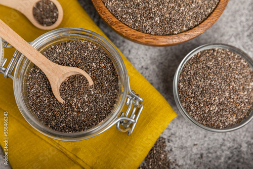 Chia seeds in a spoon and bowl on a black texture background.Superfood and axiontidant. Diet. Close-up. Place for text. Copy space.