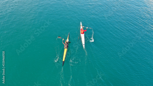 Aerial drone abstract slow shutter photo of athletes competing in sport canoe in tropical exotic lake with emerald waters