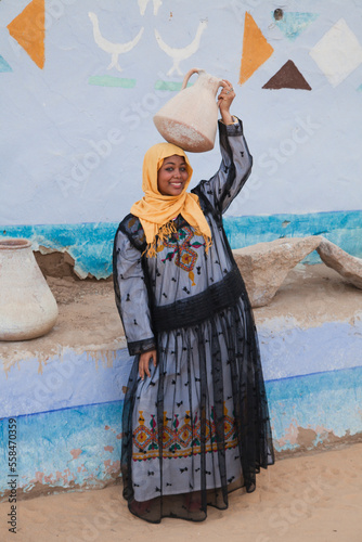 a Nubian girl holding a nile water pot in village in aswan
