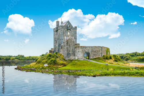 Dunguaire castle on the seashore with reflection on calm sea water during sunny day, Dunguaire, Ireland