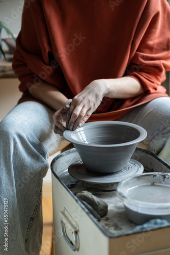 Ceramic master creating handmade stoneware on wheel in studio, making wheel-thrown ceramics, forming clay into shape. Mindful craft of pottery and art therapy concept