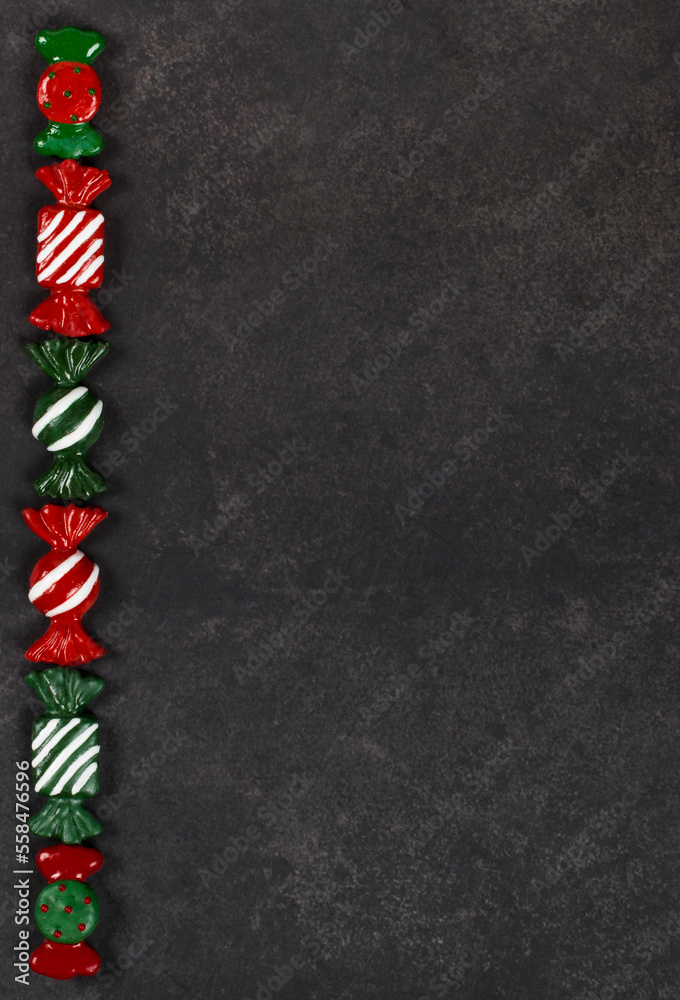 Cute sweets covered with colored icing sugar. In the form of Christmas red and green candies. Dark gray background. Top view. Copy space. New Year Cute sweets covered with colored icing sugar. In the form of Christmas red and green candies. Dark gray background. Top view. Copy space. New Year