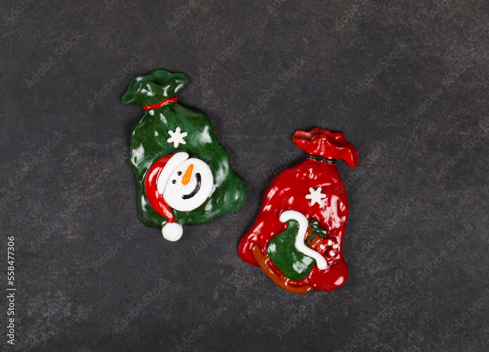 Christmas sweets covered with colored icing sugar in the shape of two Santa Claus bags with gifts. Dark gray background. Top view. New Year Christmas sweets covered with colored icing sugar in the shape of two Santa Claus bags with gifts. Dark gray background. Top view. New Year