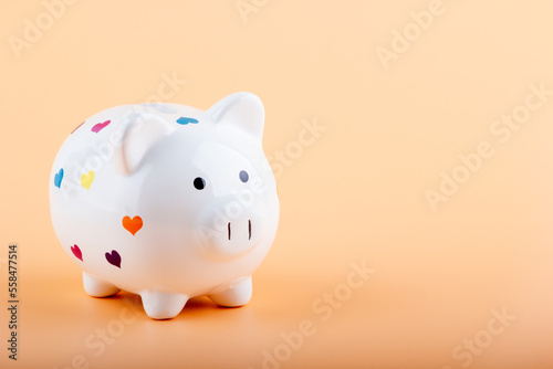 Piggy bank with multicolor hearts on a light background. Financial concept.