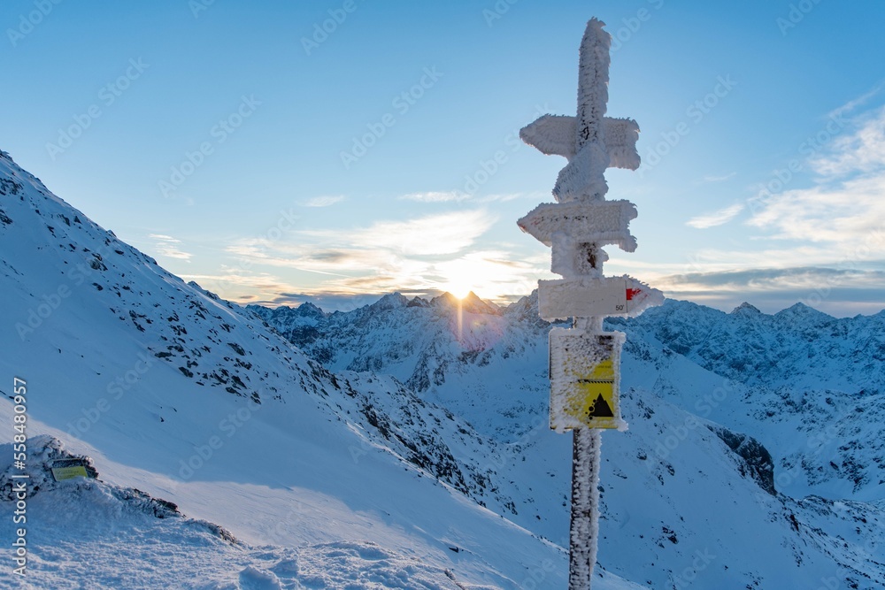 Snow covered sign marking trails on the Zawrat Pass in the winter Tatra Mountains. Winter and sunrise in Polish mountains Snow covered sign marking trails on the Zawrat Pass in the winter Tatra Mountains. Winter and sunrise in Polish mountains