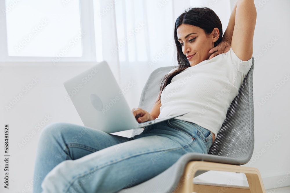 Woman freelancer works in laptop via internet over startup at home sitting on chair, technology in business