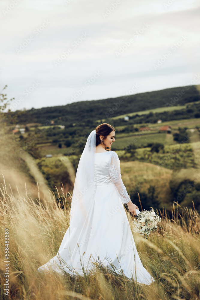a shot of a beautiful bride in a white dress in the middle of nature, the bride is holding a beautiful bouquet