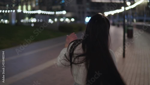 Pretty girl walks through the beautiful night city. Beautiful leady in the city. Admires the beauty of glowing multi-colored lanterns and lamps. Night City. photo