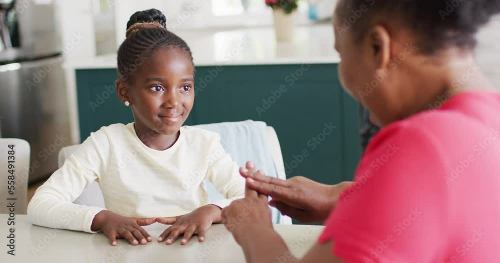 Video of smiling african american granddaughter practicing sign language with her grandmother
