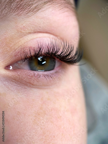 The procedure of classical eyelash extension. Beautiful female eyes close-up with long eyelashes